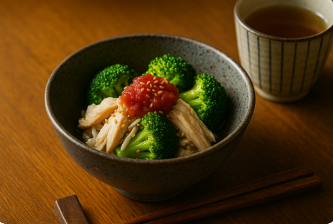 ブロッコリーとささみを梅肉とごまで和えた和風の副菜。木のテーブルと湯のみ付き