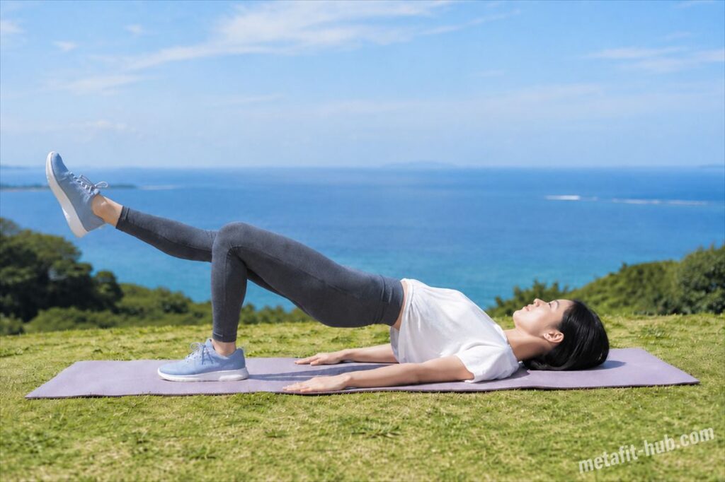 海が見える芝生の上でヨガマットを敷き、ワンレッグヒップリフトを行う女性