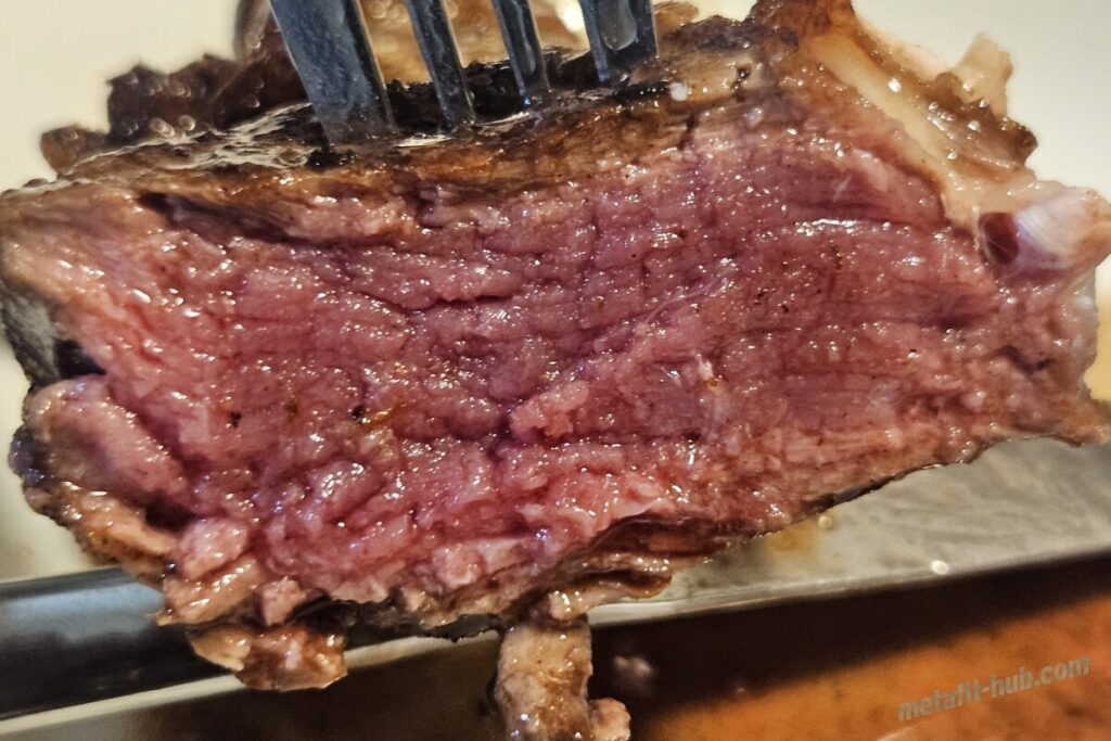 焼き上げたステーキを切った断面をアップで写し火の通り具合を確認している画像