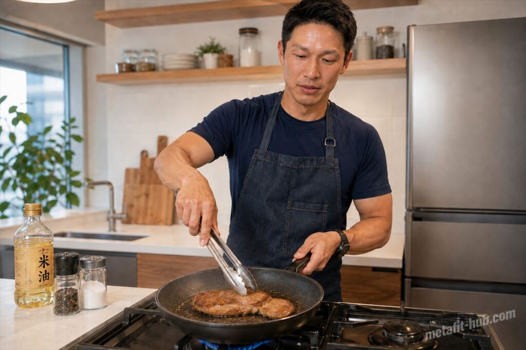 男性が自宅のキッチンでスーパーのステーキ肉をフライパンで焼いている、失敗しないステーキの焼き方記事の画像