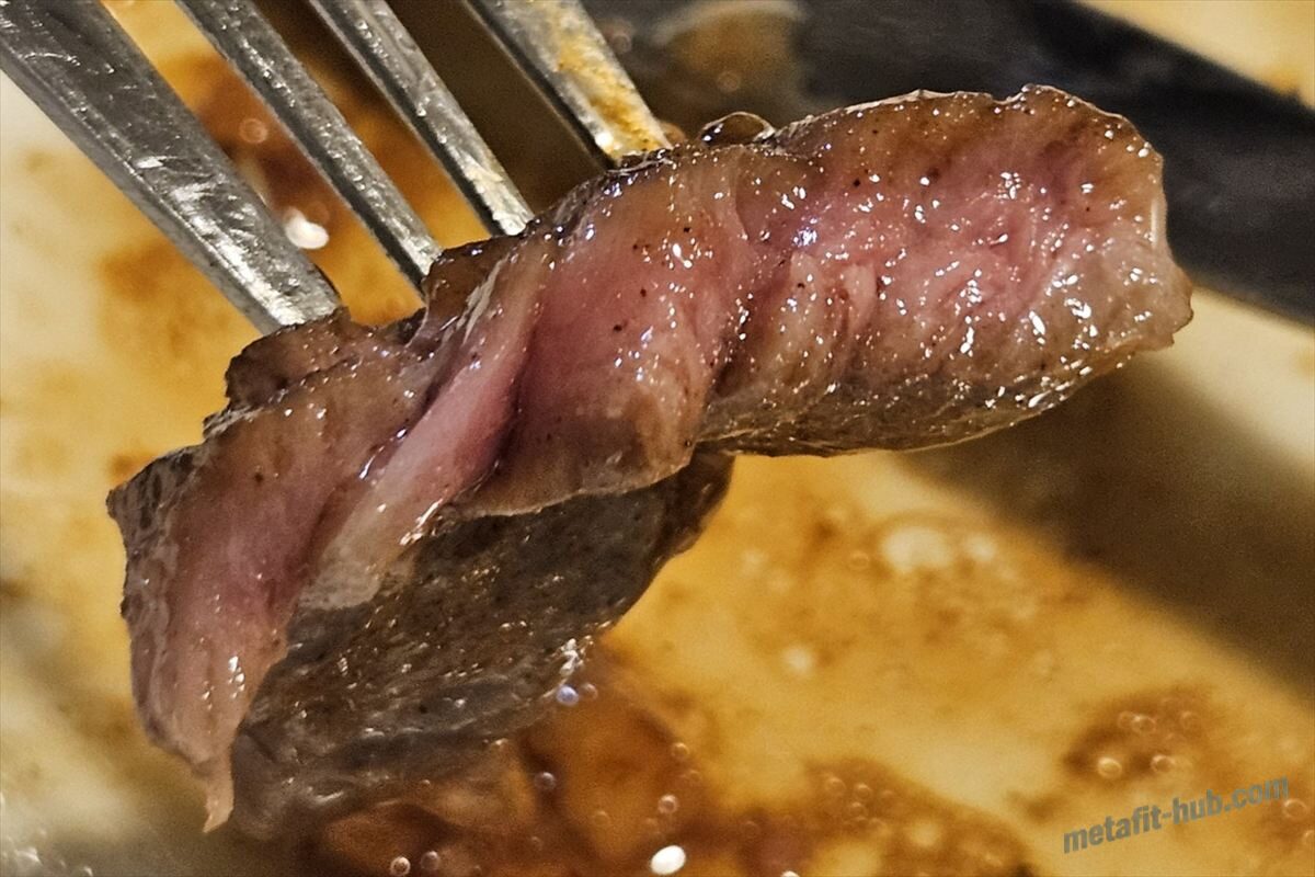 焼き上がったスーパーのステーキ肉の断面を持ち上げて焼き加減を見せている画像