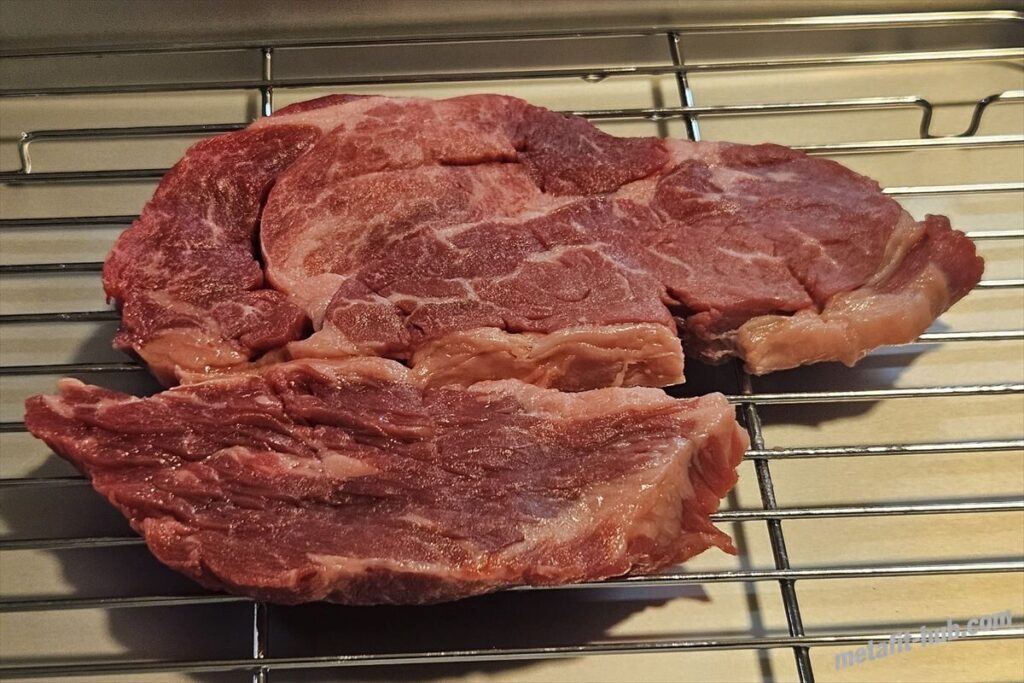 焼く前のスーパーのステーキ肉を網の上にのせて常温に戻している画像