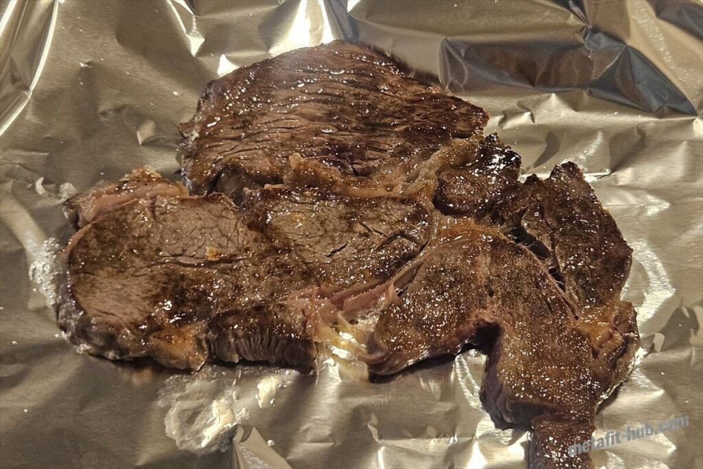 焼き上がったスーパーのステーキ肉をアルミホイルにのせて休ませている画像