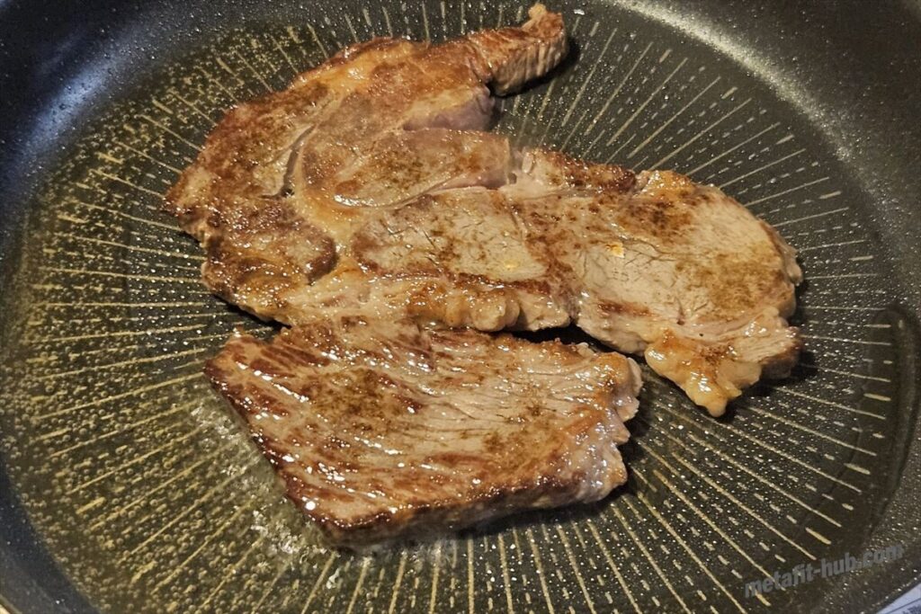 フライパンで両面に焼き色をつけたスーパーのステーキ肉の画像