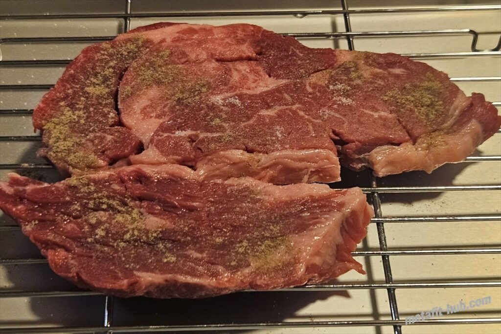 塩こしょうで下味をつけたスーパーのステーキ肉を網の上にのせた画像