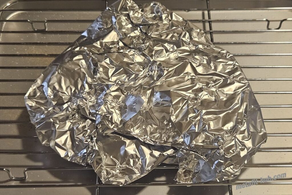 焼いたスーパーのステーキ肉をアルミホイルで包んで休ませている画像