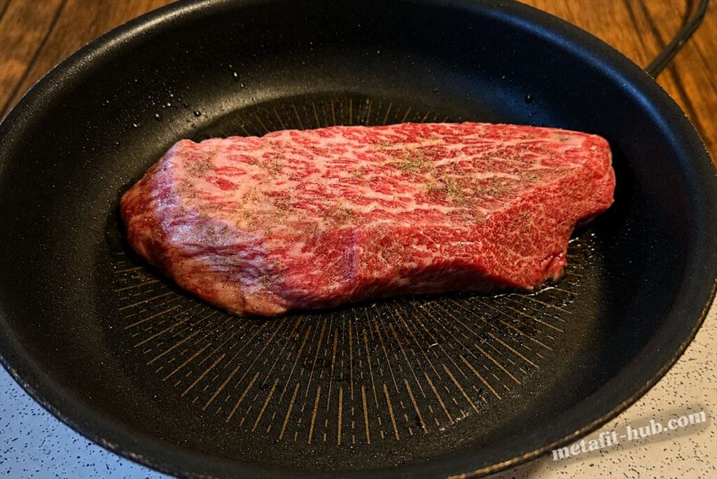 テフロンフライパンに置いた和牛ステーキに塩胡椒で下味をつけている焼き方セクションの見出し画像