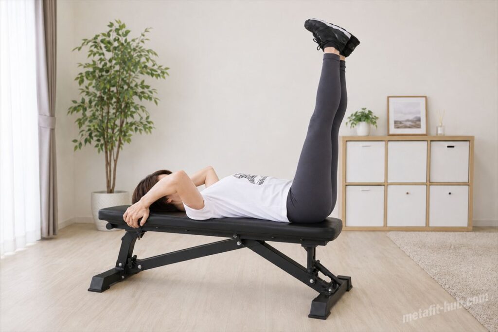自宅のベンチでレッグレイズを行う女性モデルの腹筋トレーニング風景
