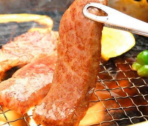 トングで持ち上げた焼き肉の画像